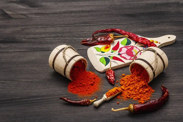 Magyar (Hungarian) red sweet and hot paprika powder. Traditional pattern on a cutting board, different varieties of dry pepper. Black wooden background — Stock Photo, Image