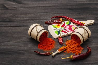 Macar (Macar) kırmızı tatlı ve sıcak kırmızı biber tozu. Kesme tahtasında geleneksel desen, farklı çeşit kuru biber. Siyah tahta arkaplan