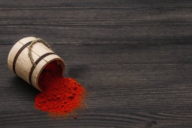 Macar (Macar) parlak kırmızı paprika tozu. Ulusal yemek pişirmek için geleneksel baharat. Tahta fıçı, siyah ahşap arka plan