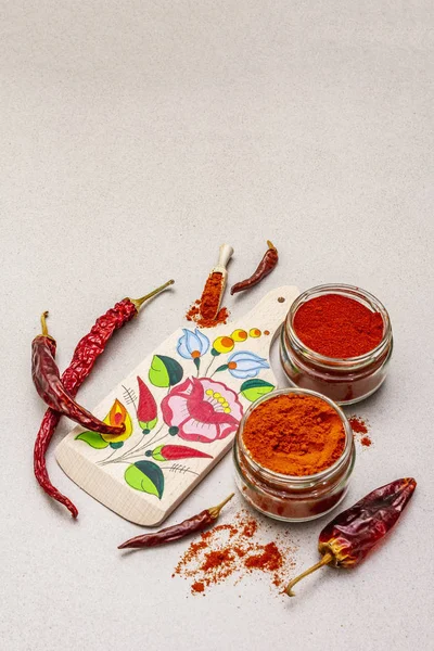Magyar (Hungarian) red sweet and hot paprika powder. Traditional pattern on a cutting board, different varieties of dry pepper. Stone concrete background — Stock Photo, Image