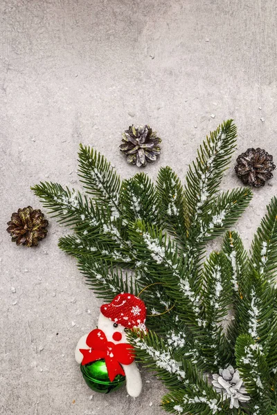 Різдвяний декоративний фон. Вічнозелена гілка ялинки, конуси, сніговик і штучний сніг. Кам'яний бетонний фон — стокове фото