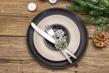 Noel ve Yeni Yıl yemekleri. Evergreen köknar ağacı dalı, mumlar, koniler, seramik tabaklar, çatal ve bıçak. Kış çatal bıçak takımı ahşap arka plan