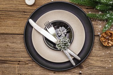 Noel ve Yeni Yıl yemekleri. Evergreen köknar ağacı dalı, mumlar, koniler, seramik tabaklar, çatal ve bıçak. Kış çatal bıçak takımı ahşap arka plan