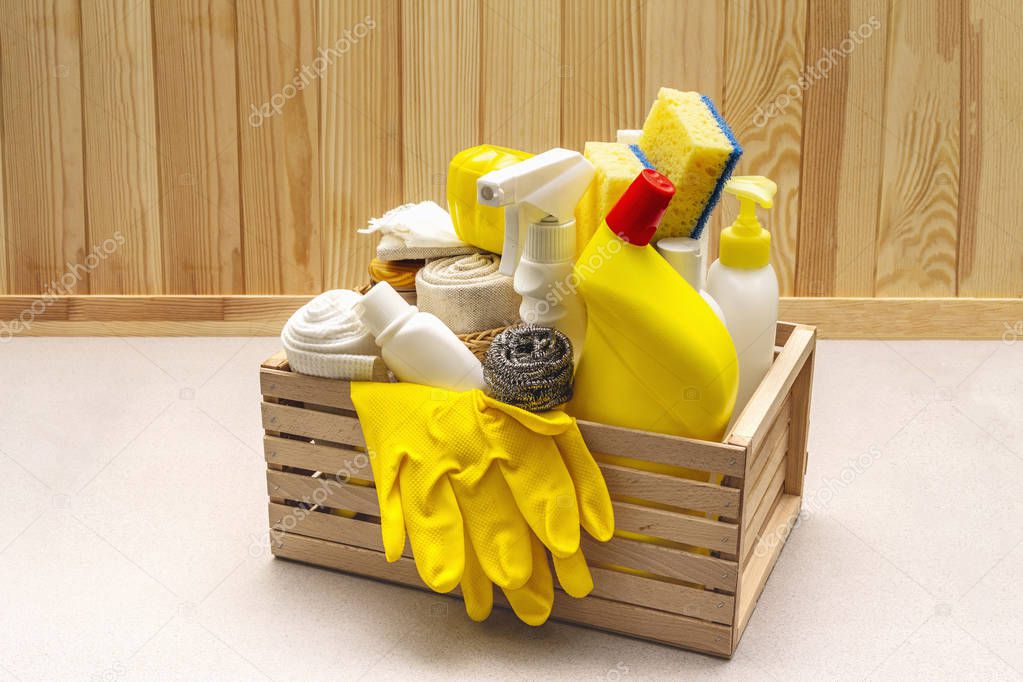 House cleaning product in wooden box. Spray, bottle, gloves, dishwashing sponge, scraper, gel air freshener. Stone concrete background