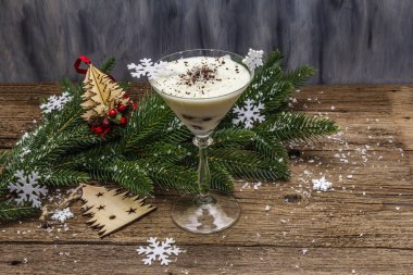 Traditional prune dessert with nuts and whipped sour cream with sugar. New Year's sweet treat concept. Wooden boards background