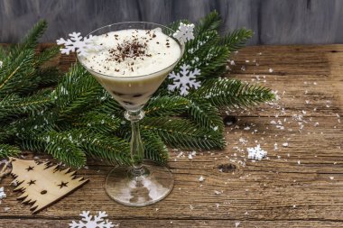 Traditional prune dessert with nuts and whipped sour cream with sugar. New Year's sweet treat concept. Wooden boards background