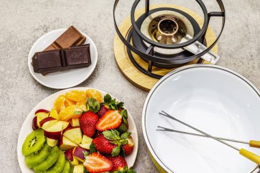 Çikolatalı fondü. Çeşitli taze meyveler, iki çeşit çikolata. Romantik tatlı pişirmek için gerekli malzemeler. Taş beton arka plan