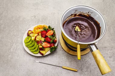 Çikolatalı fondü. Çeşitli taze meyveler, iki çeşit çikolata. Romantik tatlı pişirmek için gerekli malzemeler. Taş beton arka plan