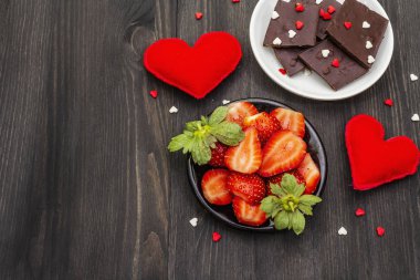 Sevgililer Günü romantik konsepti. Çikolata, taze olgun çilek, kırmızı keçeli kalp. Aşıklar için tatlı. Siyah tahta arkaplan