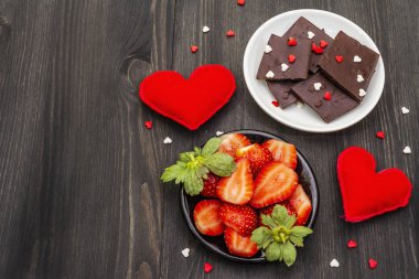 Sevgililer Günü romantik konsepti. Çikolata, taze olgun çilek, kırmızı keçeli kalp. Aşıklar için tatlı. Siyah tahta arkaplan