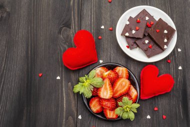 Sevgililer Günü romantik konsepti. Çikolata, taze olgun çilek, kırmızı keçeli kalp. Aşıklar için tatlı. Siyah tahta arkaplan