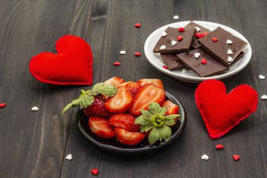 Sevgililer Günü romantik konsepti. Çikolata, taze olgun çilek, kırmızı keçeli kalp. Aşıklar için tatlı. Siyah tahta arkaplan