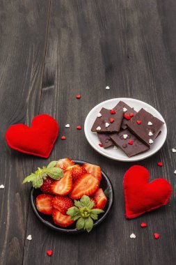 Sevgililer Günü romantik konsepti. Çikolata, taze olgun çilek, kırmızı keçeli kalp. Aşıklar için tatlı. Siyah tahta arkaplan