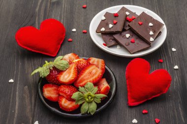 Sevgililer Günü romantik konsepti. Çikolata, taze olgun çilek, kırmızı keçeli kalp. Aşıklar için tatlı. Siyah tahta arkaplan