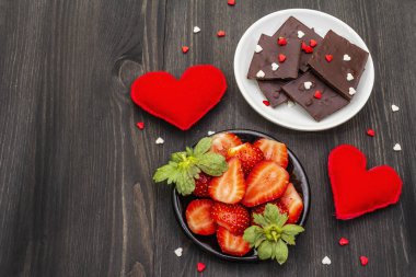 Sevgililer Günü romantik konsepti. Çikolata, taze olgun çilek, kırmızı keçeli kalp. Aşıklar için tatlı. Siyah tahta arkaplan