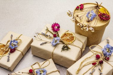 Zero waste gift concept. Valentine Day or Birthday eco friendly packaging. Festive boxes in craft paper with different organic decorations. Stone concrete background
