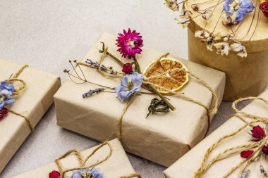 Zero waste gift concept. Valentine Day or Birthday eco friendly packaging. Festive boxes in craft paper with different organic decorations. Stone concrete background