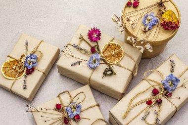 Zero waste gift concept. Valentine Day or Birthday eco friendly packaging. Festive boxes in craft paper with different organic decorations. Stone concrete background