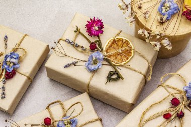 Zero waste gift concept. Valentine Day or Birthday eco friendly packaging. Festive boxes in craft paper with different organic decorations. Stone concrete background