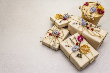 Zero waste gift concept. Valentine Day or Birthday eco friendly packaging. Festive boxes in craft paper with different organic decorations. Stone concrete background