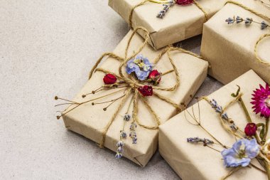 Zero waste gift concept. Valentine Day or Birthday eco friendly packaging. Festive boxes in craft paper with different organic decorations. Stone concrete background