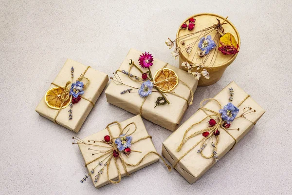 Zero waste gift concept. Valentine Day or Birthday eco friendly packaging. Festive boxes in craft paper with different organic decorations. Stone concrete background — 스톡 사진