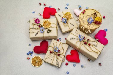 Zero waste gift concept. Valentine Day or Birthday eco friendly packaging. Festive boxes in craft paper with different organic decorations. Stone concrete background