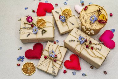 Zero waste gift concept. Valentine Day or Birthday eco friendly packaging. Festive boxes in craft paper with different organic decorations. Stone concrete background