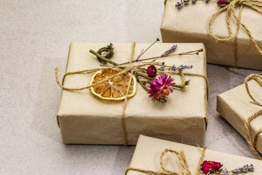 Zero waste gift concept. Valentine Day or Birthday eco friendly packaging. Festive boxes in craft paper with different organic decorations. Stone concrete background
