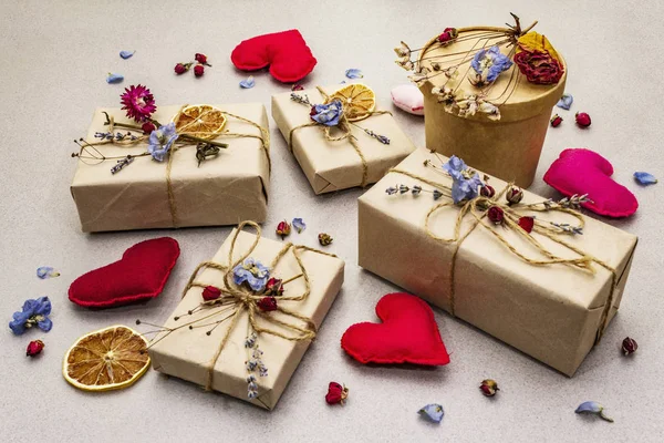 Concetto regalo zero rifiuti. Imballaggio ecologico di San Valentino o compleanno. Scatole festive in carta artigianale con diverse decorazioni organiche. Pietra sfondo concreto — Foto Stock