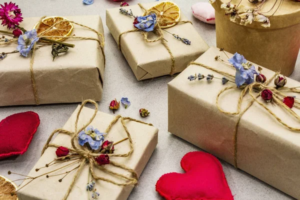 Concetto regalo zero rifiuti. Imballaggio ecologico di San Valentino o compleanno. Scatole festive in carta artigianale con diverse decorazioni organiche. Pietra sfondo concreto — Foto Stock