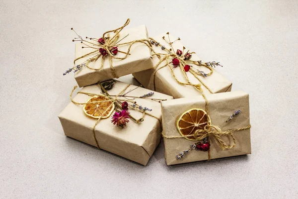 Zero waste gift concept. Valentine Day or Birthday eco friendly packaging. Festive boxes in craft paper with different organic decorations. Stone concrete background