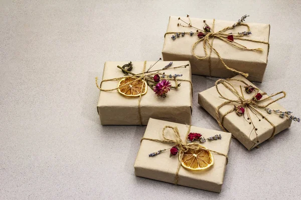 Zero waste gift concept. Valentine Day or Birthday eco friendly packaging. Festive boxes in craft paper with different organic decorations. Stone concrete background