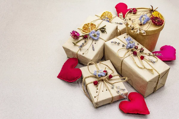 Zero waste gift concept. Valentine Day or Birthday eco friendly packaging. Festive boxes in craft paper with different organic decorations. Stone concrete background — 스톡 사진