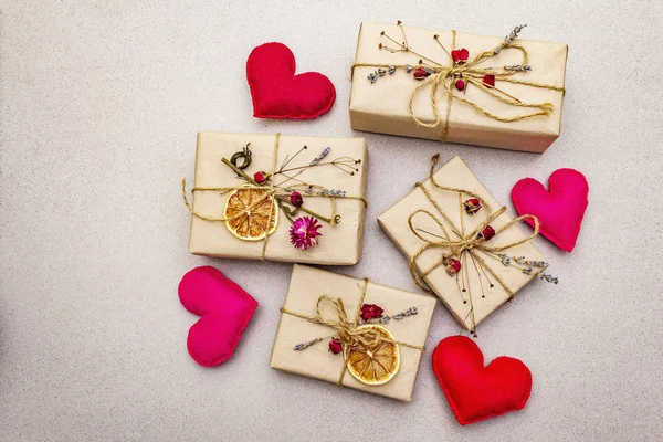 Zero waste gift concept. Valentine Day or Birthday eco friendly packaging. Festive boxes in craft paper with different organic decorations. Stone concrete background — 스톡 사진