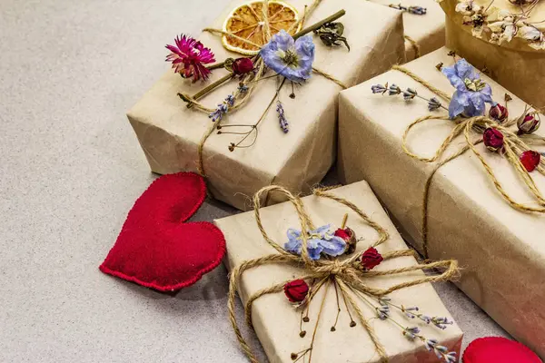 Concetto regalo zero rifiuti. Imballaggio ecologico di San Valentino o compleanno. Scatole festive in carta artigianale con diverse decorazioni organiche. Pietra sfondo concreto — Foto Stock