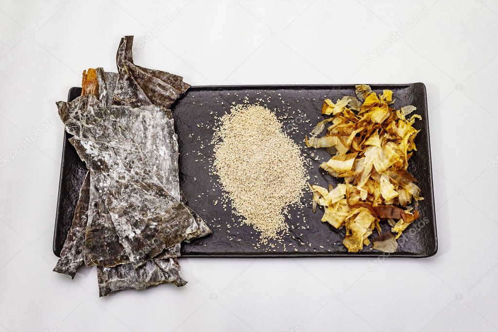 Set of traditional Japanese ingredient for cooking basic dashi broth. Algae kombu, katsuobushi and finished dry granules. Isolated on white background