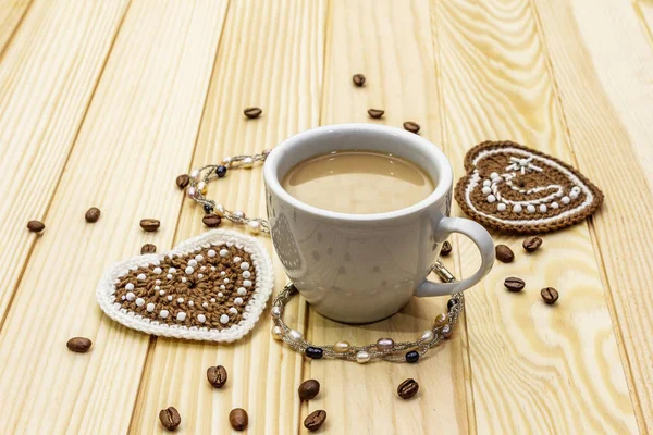 Sevgililer Günü konsepti. Bir fincan kahve, örgü kalp, bir dizi inci boncuk. Romantik kahvaltı ve tahtadan yapılmış bir hediye. — Stok fotoğraf