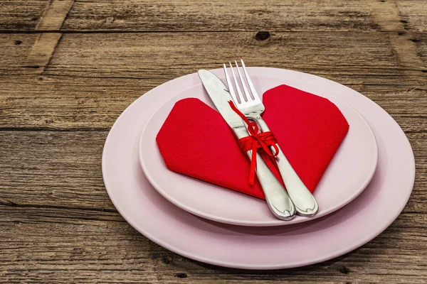 Romantikus vacsora asztal tányérokkal és szív alakú szalvétával. Szerelmi koncepció Valentin-napra vagy anyák napjára, esküvői evőeszközök. Vintage fa táblák háttér — Stock Fotó