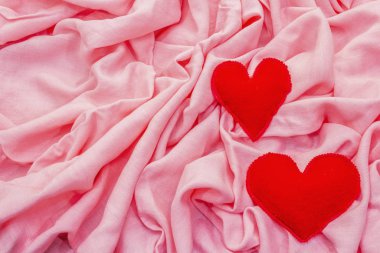Sevgililer Günü ya da düğün kartı konsepti. Romantik tasarım, kırmızı keçeli kalpler. Pembe kumaş arkaplanı