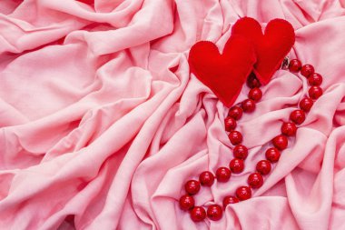 Sevgililer Günü ya da düğün kartı konsepti. Romantik tasarım, kırmızı keçeli kalpler, boncuklar. Pembe kumaş arkaplanı