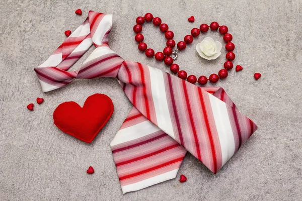 Valentines Day concept. Red felt hearts, women beads, men tie. Stone concrete background — 스톡 사진