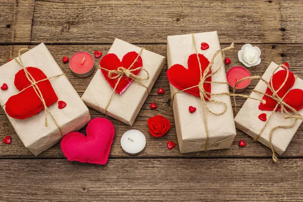 Concetto regalo zero rifiuti. Imballaggio ecologico San Valentino o Wedding. Scatole festive in carta artigianale con cuori di feltro rosso. Vintage sfondo in legno — Foto Stock