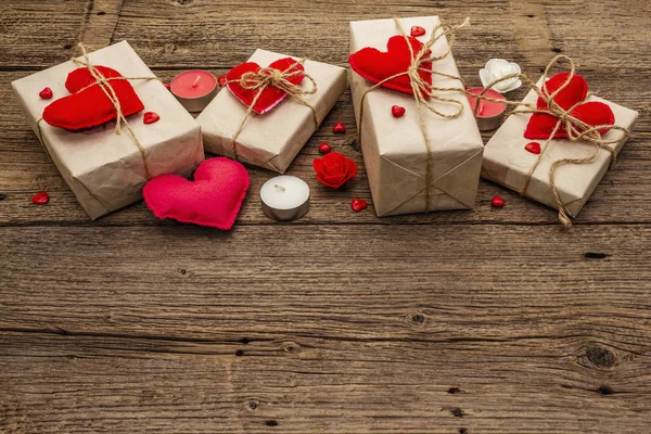 Concetto regalo zero rifiuti. Imballaggio ecologico San Valentino o Wedding. Scatole festive in carta artigianale con cuori di feltro rosso. Vintage sfondo in legno — Foto Stock