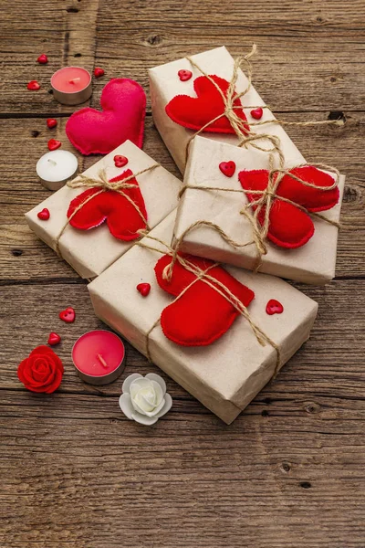 Concetto regalo zero rifiuti. Imballaggio ecologico San Valentino o Wedding. Scatole festive in carta artigianale con cuori di feltro rosso. Vintage sfondo in legno — Foto Stock