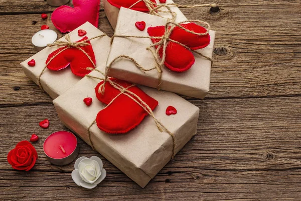 Concetto regalo zero rifiuti. Imballaggio ecologico San Valentino o Wedding. Scatole festive in carta artigianale con cuori di feltro rosso. Vintage sfondo in legno — Foto Stock