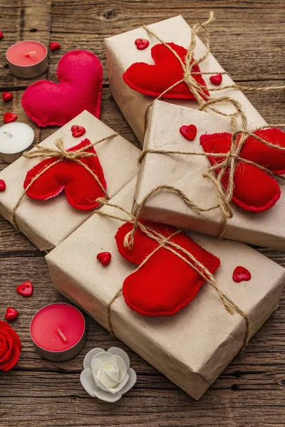 Zero waste gift concept. Valentine Day or Wedding eco friendly packaging. Festive boxes in craft paper with red felt hearts. Vintage wooden background
