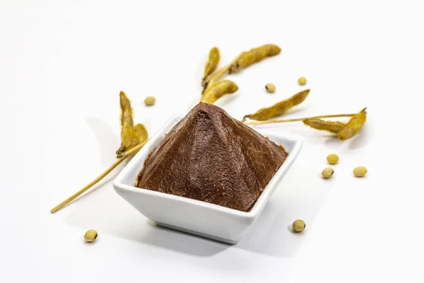 Açık kahverengi miso macunu beyaz arkaplanda izole edilmiş. Geleneksel Japon baharatı, kuru soya fasulyesi kabukları.
