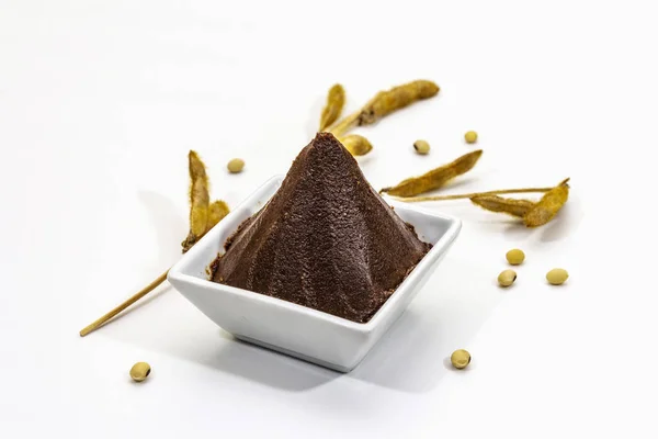 Pasta de miso marrón oscuro aislada sobre fondo blanco. Sazonador japonés tradicional, vainas de soja seca — Foto de Stock