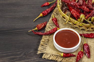 Kavanozda acı biber sosu ve farklı çeşitte acı biber. Hazırlık için ana malzeme. Siyah ahşap aşçılık arka planı